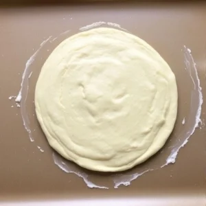Transfer the dough onto the prepared baking sheet and shape it into a round pizza crust, about ½-inch thick.