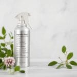 Magnesium spray ingredients: magnesium chloride flakes, essential oils, and distilled water next to a glass spray bottle for a relaxing, DIY magnesium spray recipe.