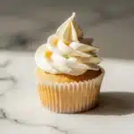 Smooth cream cheese buttercream frosting piped in decorative swirls on vanilla cupcakes with professional food photography