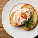 Creamy pimento cheese recipe with cream cheese spread on golden crispy crostini with pimento garnish